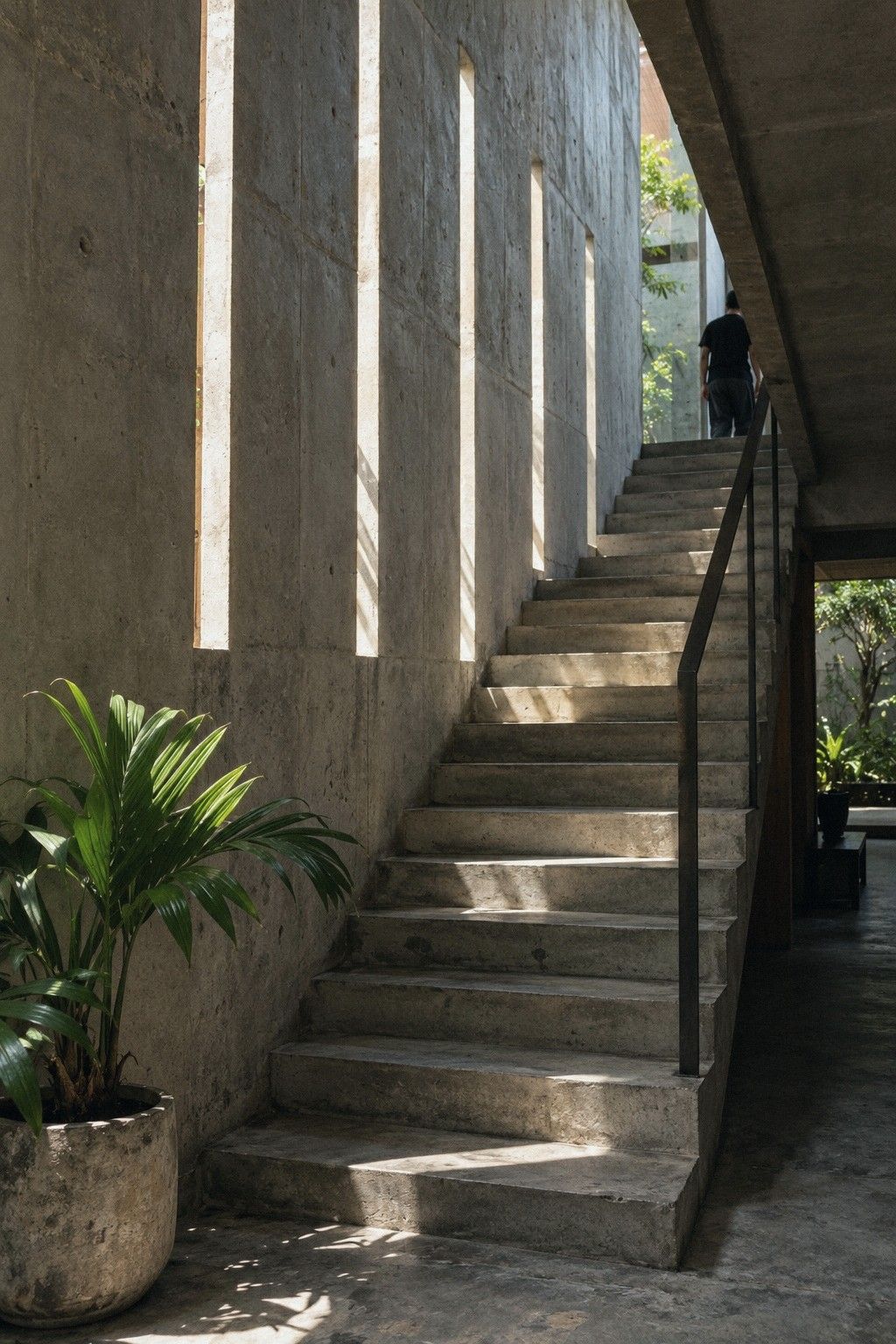 A steel and timber stair rising beside a white wall, lit from above